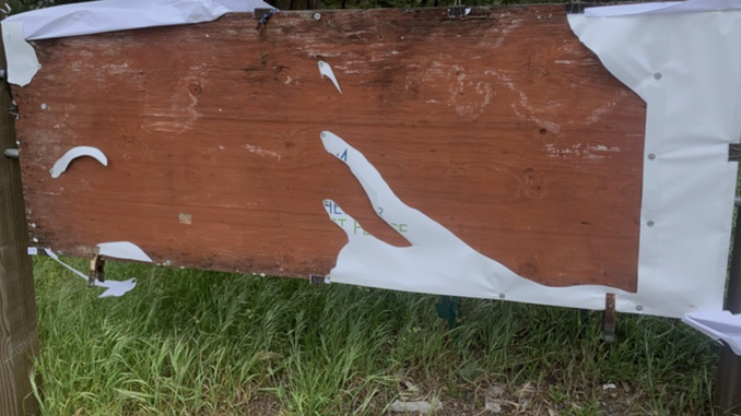 a brown wooden board with pieces of a white banner left